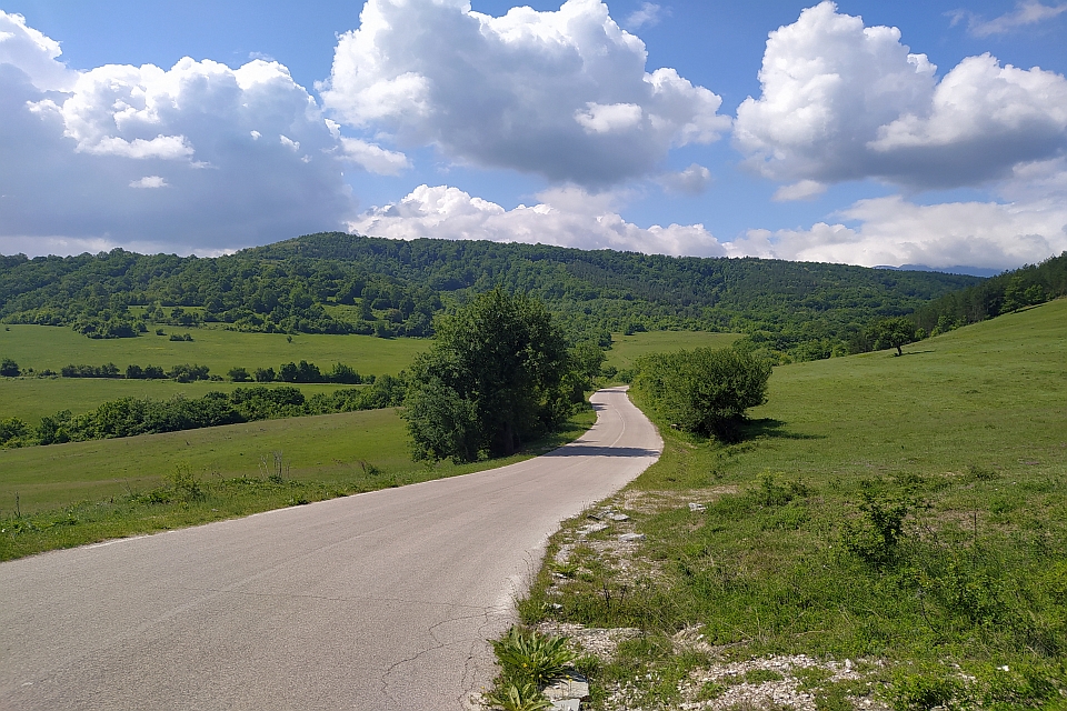 Paved Road Winds Through A Lush Green Valley