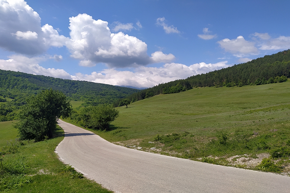Paved Road Winds Through A Lush Green Valley