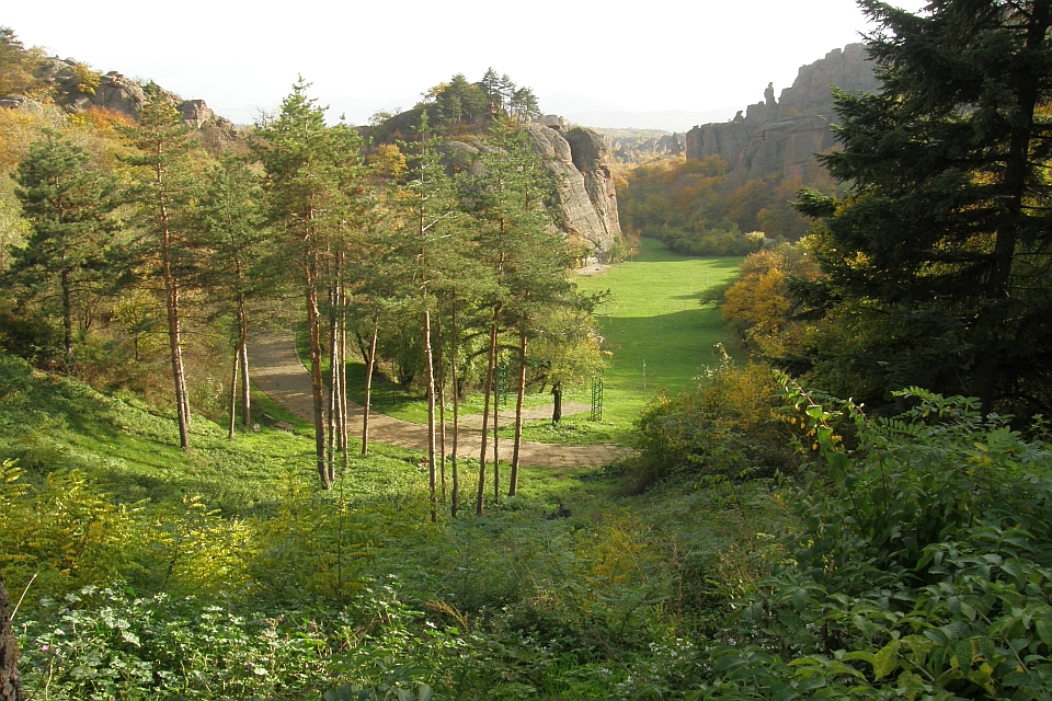 Grassy Field Nestled Between Steep, Rocky Cliffs