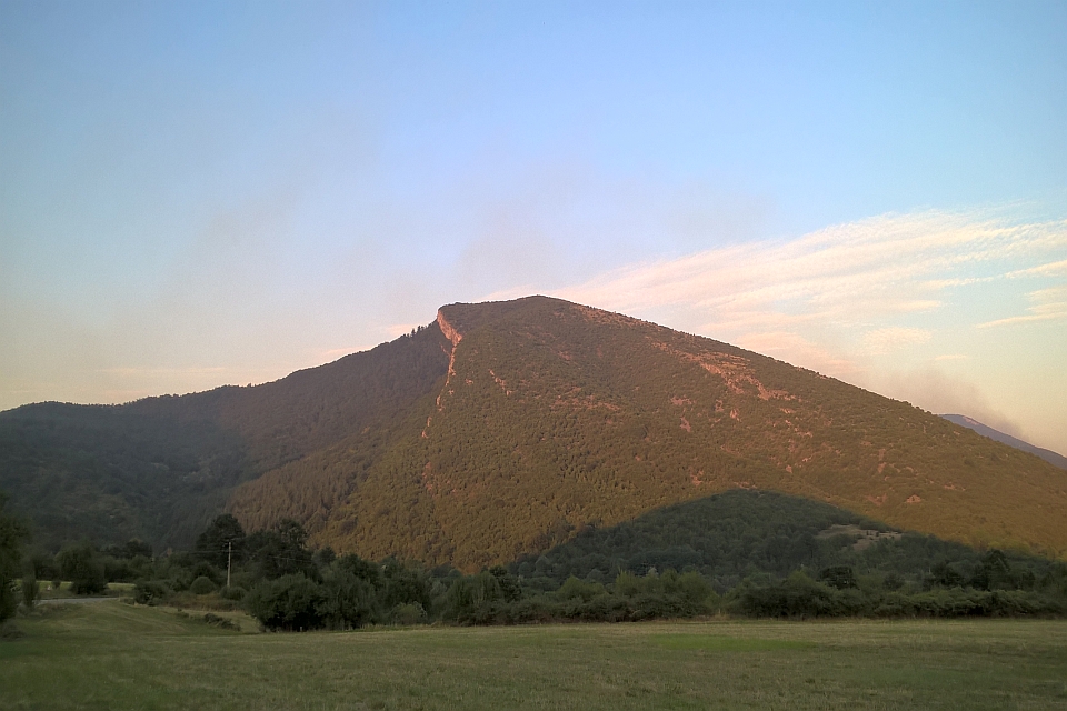 Forested Mountain Under A Pale Blue Sky