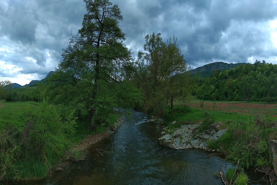 Small River Flows Through A Lush Green Valley